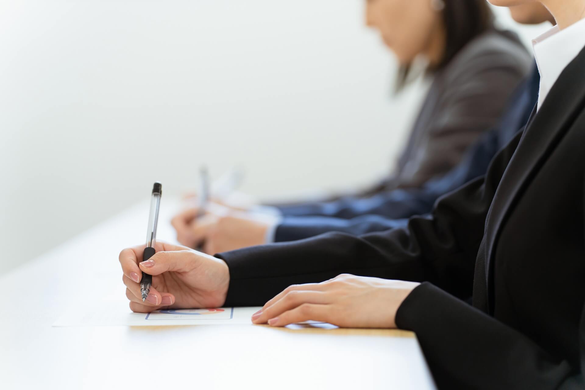 会議でメモを取るビジネススーツの男性