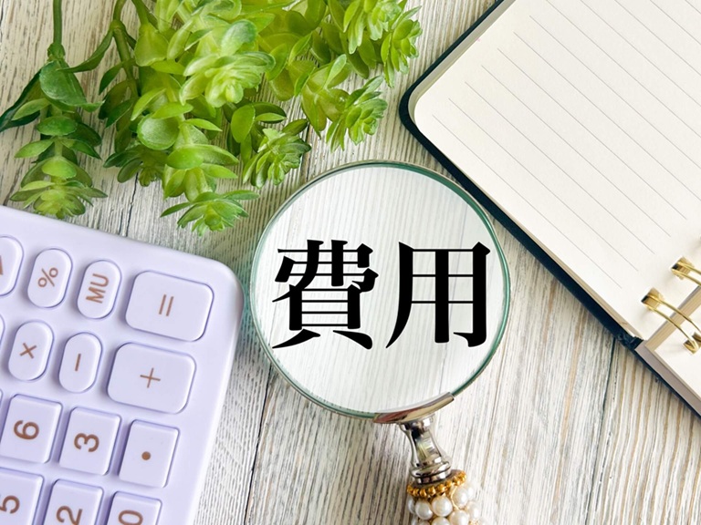 白いデスク上の電卓と費用のメモ