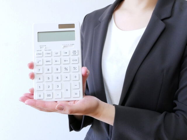 白い電卓を持つビジネススーツの女性