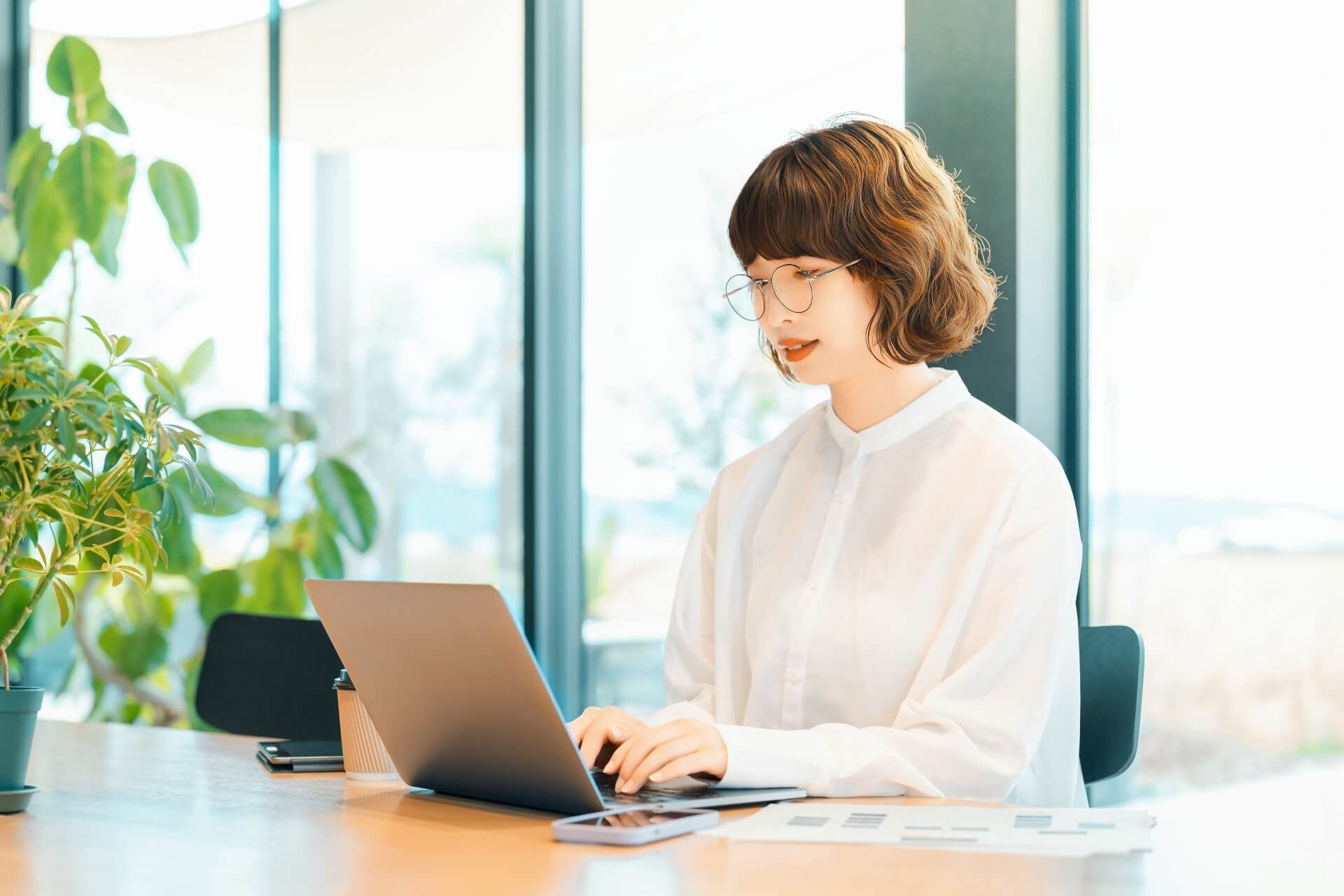 窓辺でノートパソコンを操作する女性